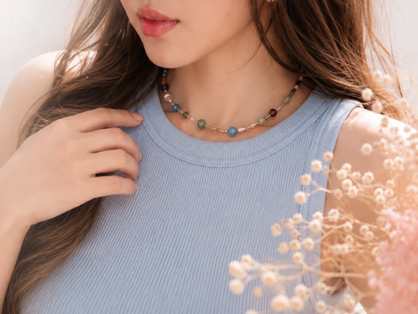 A close-up of a Lumoraah customer wearing a handmade beaded necklace, soft window light on her collarbone