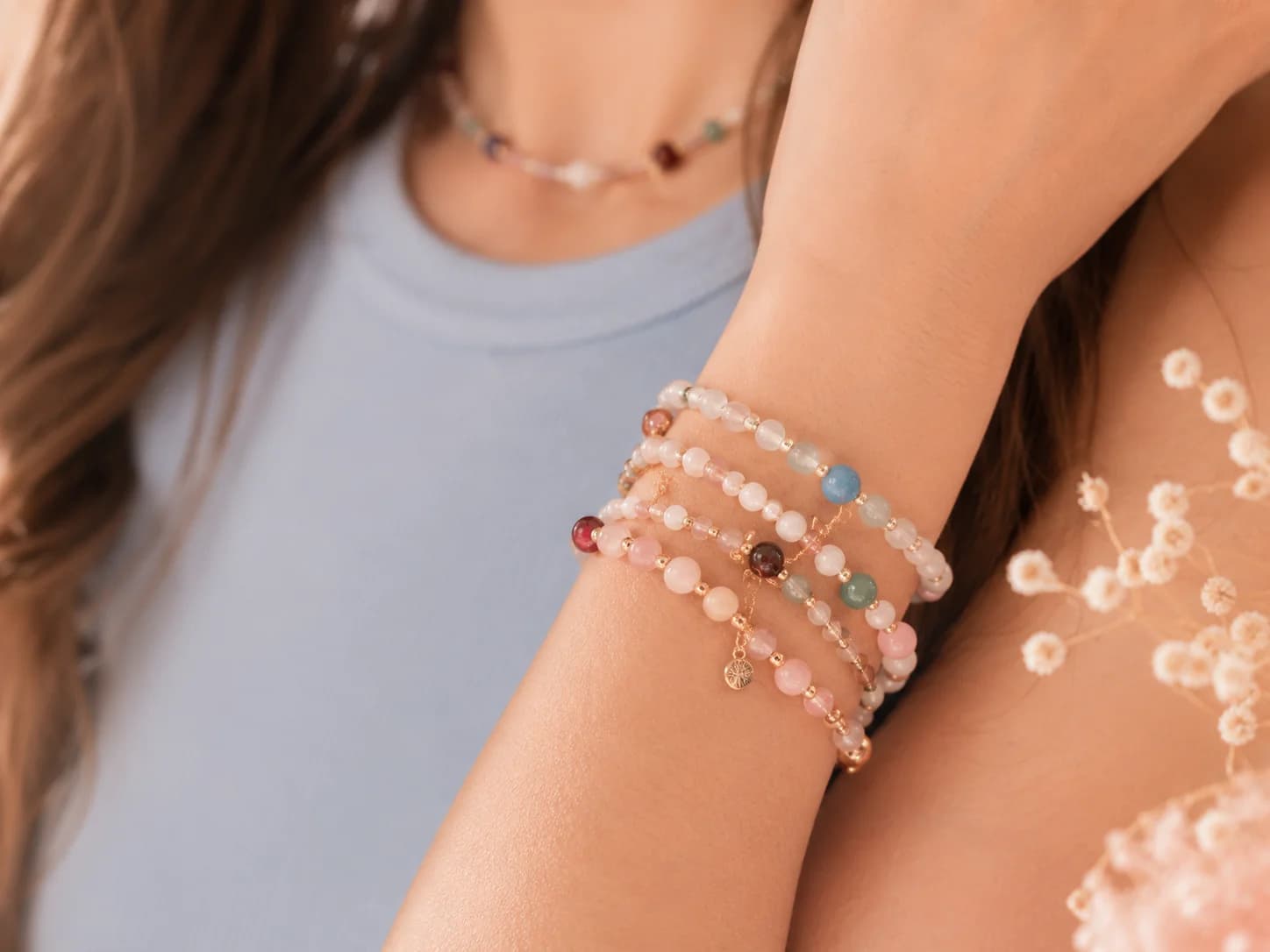 A stack of pastel beaded bracelets worn on a wrist